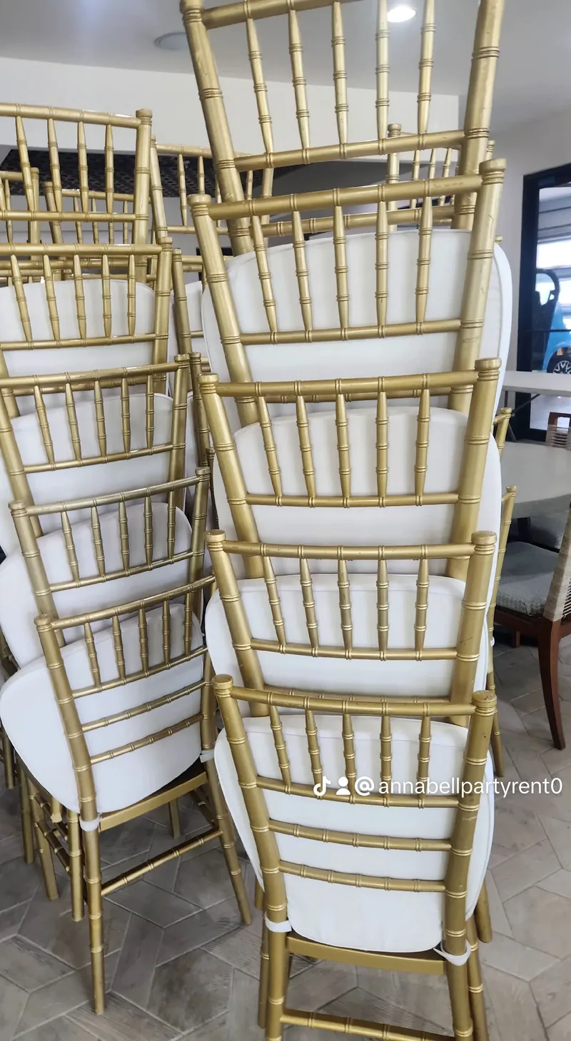 Stacked gold chiavari chairs with white cushions
