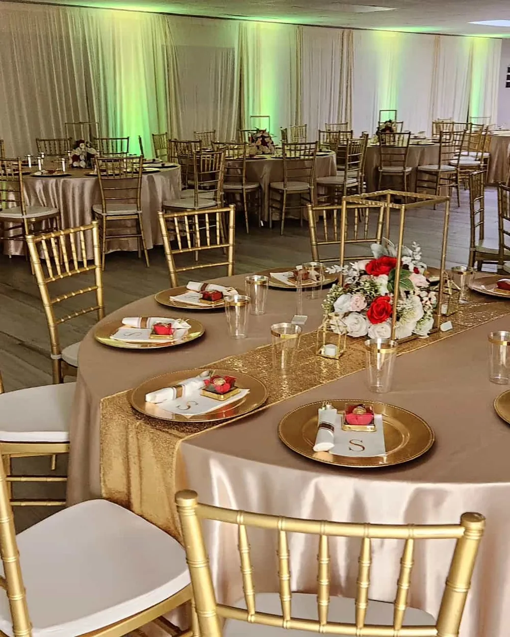 Banquet hall set with gold chiavari chairs, round tables and uplighting