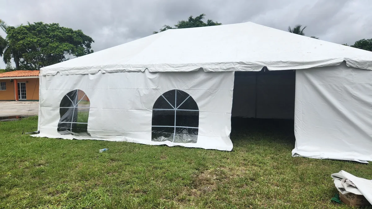 White event tent with window sidewalls set up on a lawn